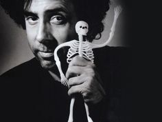 a black and white photo of a man holding a skeleton toy