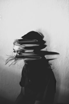 black and white photograph of woman's head with hair blowing in the wind on wall