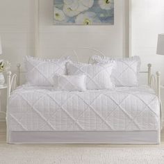 a white daybed with four pillows and two night stands on the side of it