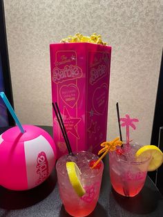 two cocktails are sitting on a table next to a pink bag and a ball