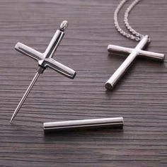 two cross pendants sitting on top of a wooden table