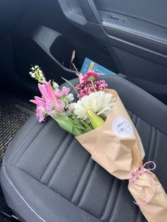 a bouquet of flowers sitting on the back seat of a car, wrapped in brown paper