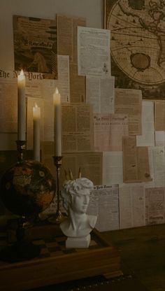 a table topped with a busturine next to a wall covered in papers and candles