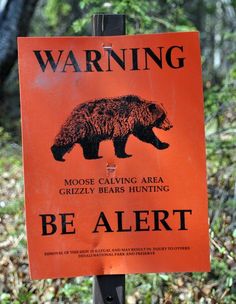 a warning sign posted on a post in the woods