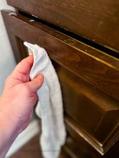 someone is wiping up some white cloth on the dresser drawer knobs in their home