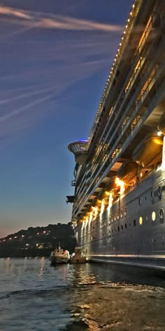 a large cruise ship docked in the water at night with lights on it's side