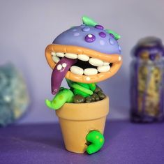 an odd looking toy is sitting in a flower pot with its mouth open and tongue out