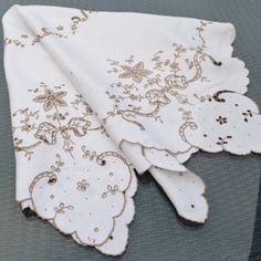 two white napkins with brown designs on them sitting on top of a gray surface