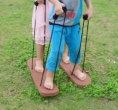 two young children standing in the grass with crutches on their feet and one holding onto another child's leg