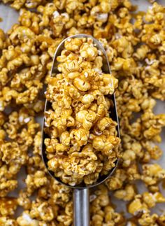 a spoon filled with caramel popcorn on top of a table