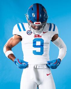 a football player wearing a white uniform and blue gloves with his hands on his hips