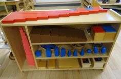 a toy house made out of legos on a wooden shelf in a playroom