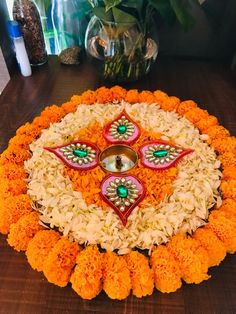 a decorative flower arrangement with an oil lamp in the center on a wooden table next to flowers