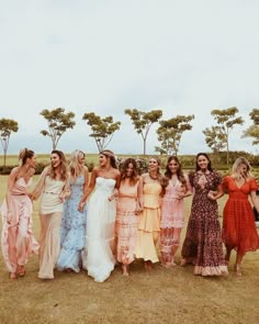 a group of women standing next to each other on top of a grass covered field