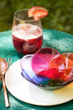 a plate with fruit on it next to a glass filled with ice and water sitting on top of a table