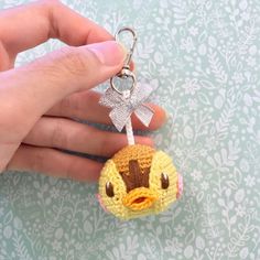 a hand holding a tiny crocheted bird keychain