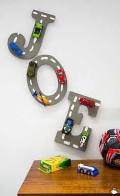 a wooden table topped with toy cars next to a wall mounted sign that says joy