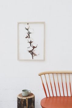 two chairs and a table in front of a white wall with a painting on it