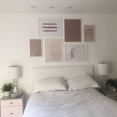 a white bed sitting in a bedroom next to two nightstands and pictures on the wall