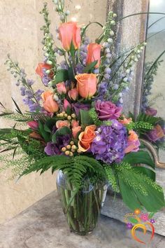 a glass vase filled with lots of flowers on top of a marble counter next to a mirror