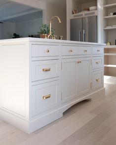 a kitchen with white cabinets and gold pulls on the doors, counter tops and drawers