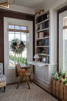 a living room filled with furniture and bookshelves next to a window covered in plants