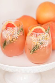 three glasses filled with watermelon and rosemary garnish on a white plate