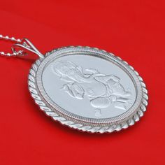 "A gorgeous sterling silver necklace, set with an authentic 1 oz Silver Round - Ganesha. Obverse: Traditional image of Ganesha attended by a mouse, which is commonly seen. Reverse: Hindi text for \"Hinduism,\" along with the weight, purity and year of issue. The coin bezel frame is well designed with classic ropes, about 2.32\"(59mm) x 1.84\"(47mm), and made of solid 925 sterling silver. It comes with a 24\" 925 sterling silver chain and also a beautiful gift box, so the pendant is ready to wear Traditional Round Necklace With Polished Finish, Sterling Silver Jewelry For Festivals As A Gift, Sterling Silver Jewelry For Festivals And Gifts, Silver Amulet Jewelry For Diwali, Silver Amulet Necklace For Diwali, Engraved Temple Jewelry As A Gift, Traditional Medallion Necklace With Polished Finish, Traditional Polished Wedding Necklace, Traditional Sterling Silver Jewelry With Coin Pendant