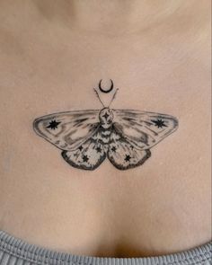 a moth tattoo on the chest with stars and a crescent moon in the center is shown