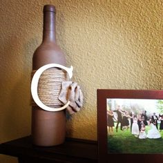 a photo and a wine bottle sitting on a shelf next to a frame with the letter o