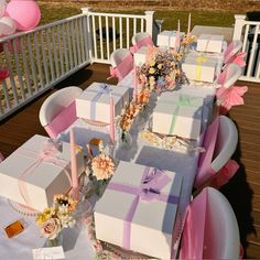 a table set up for a baby shower with pink and white boxes on it's tables