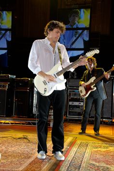 two men are playing guitars on stage