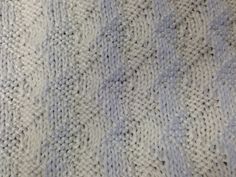 a close up view of a knitted blanket with blue and white stripes on it