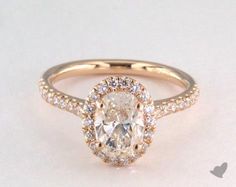 an oval cut diamond ring with halos on the band and shoulders, set in yellow gold