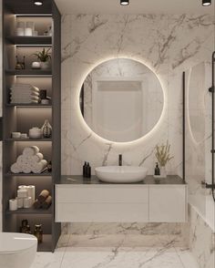 a bathroom with marble walls and flooring has a round mirror on the wall above the sink