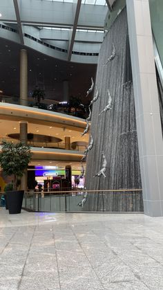 the inside of a building with a large waterfall in it's center and people walking around