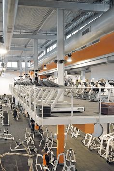 an indoor gym with rows of exercise machines and treadmills in the foreground