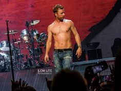 a shirtless man standing in front of a stage