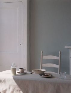 a table with two cups and plates on it in front of a door that leads to another room