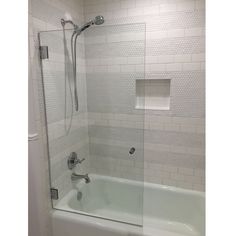 a bath tub sitting next to a shower with a glass door on the back wall