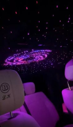 the interior of a car with purple lights and stars on the ceiling in the dark