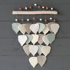 a group of ceramic hearts hanging from a string on a gray wooden wall with beads