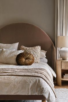 a bed with white sheets and pillows on top of it next to a night stand