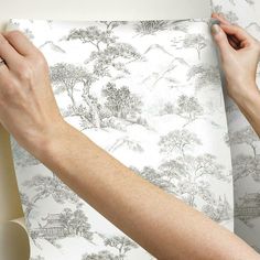 a person is wrapping up a wallpaper with black and white trees on it,