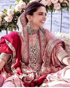 a woman in a pink and red outfit sitting on top of a bed next to flowers