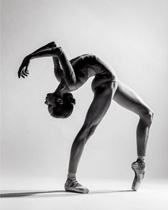 a black and white photo of a woman doing a handstand on one leg