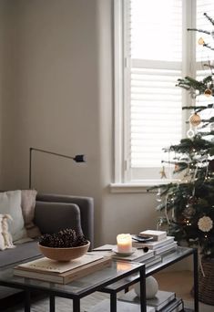 a living room with a christmas tree in the corner and candles on the coffee table