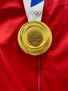 a gold medal is placed on top of a red jacket with the olympic logo in the center