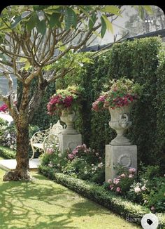 two stone urns are in the middle of a garden