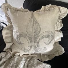 a pillow with a fleur de lis design on it sitting on a couch